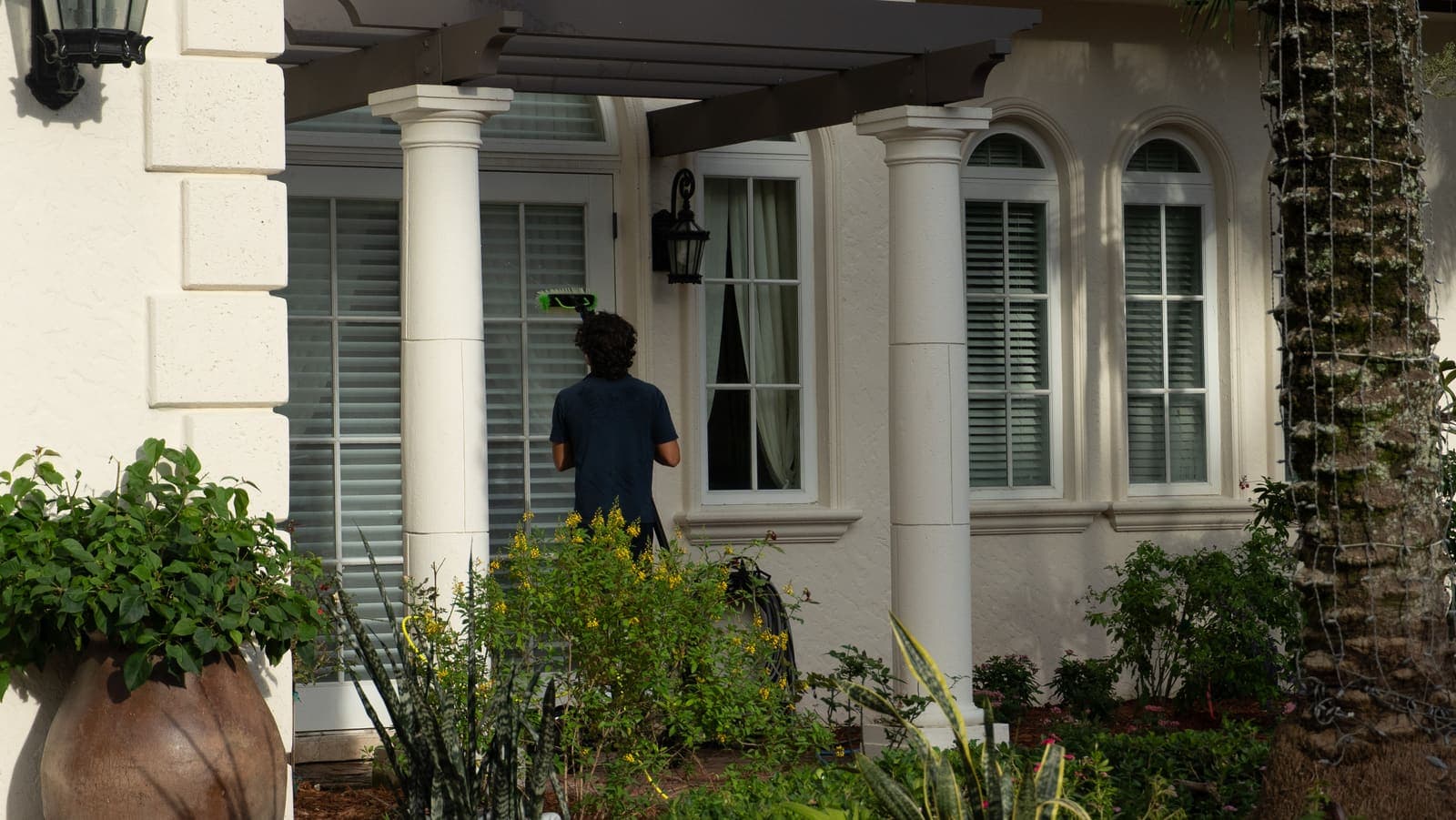 Coast technician cleaning tall entry windows at a Miami home