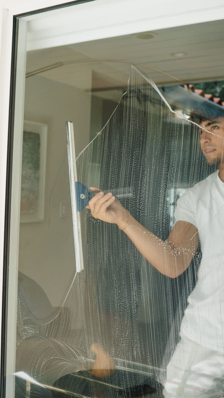 Coast technician squeegeeing the inside of a large window in a Miami home