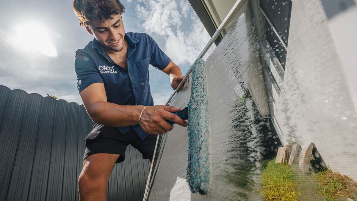 Coast technician scrubbing a window screen with a soft wet mop
