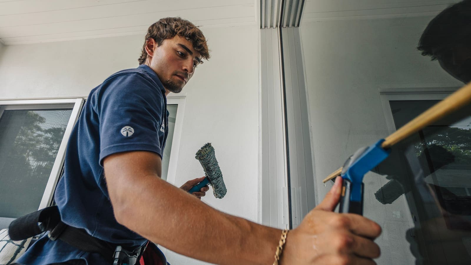 Coast technician holding the wetted mop and brass squeegee at a patio door