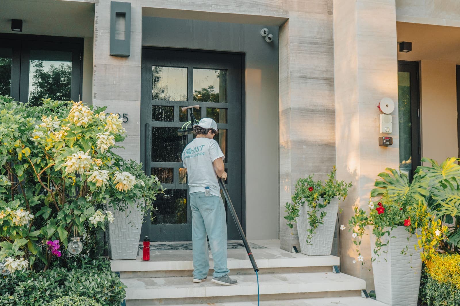 Coast technician cleaning the glass front door and sidelights of a Miami home by hand